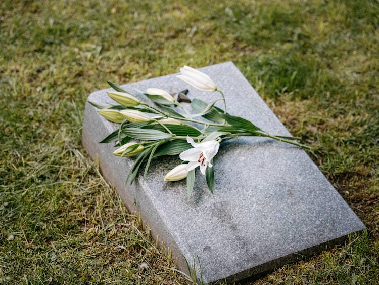 Flower placed on granite flat grave marker in grassy yard