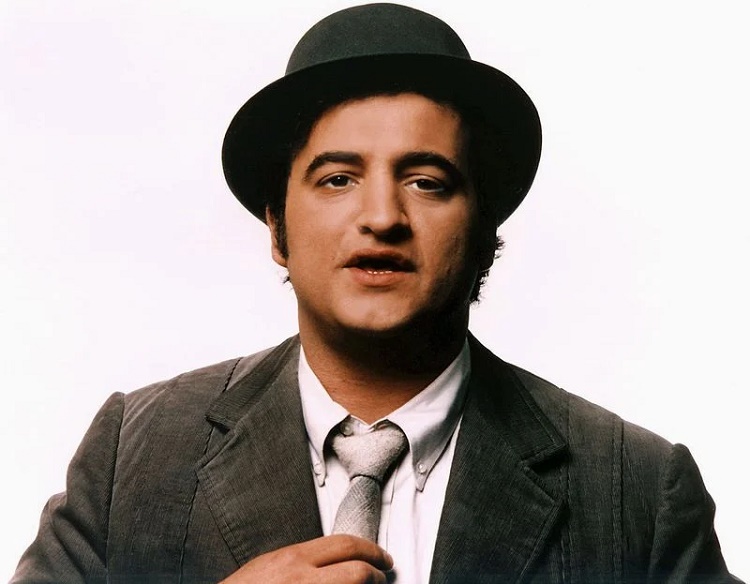 Actor John Belushi posing in black fedora, gray blazer, dress shirt and white tie