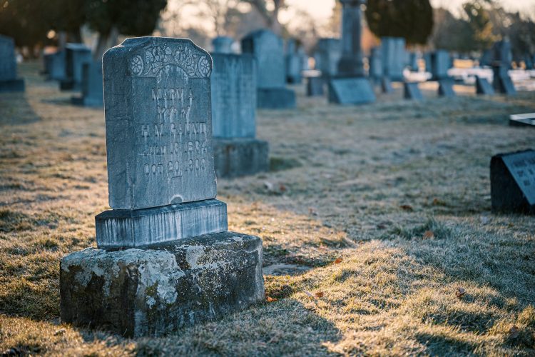 Engraved granite tombstone with damaged inscription in outdoor graveyard